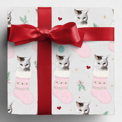 Gift wrapped in Santa's Stocking Stuffers personalised paper with a red bow, showing a cat's face in pink Christmas stockings