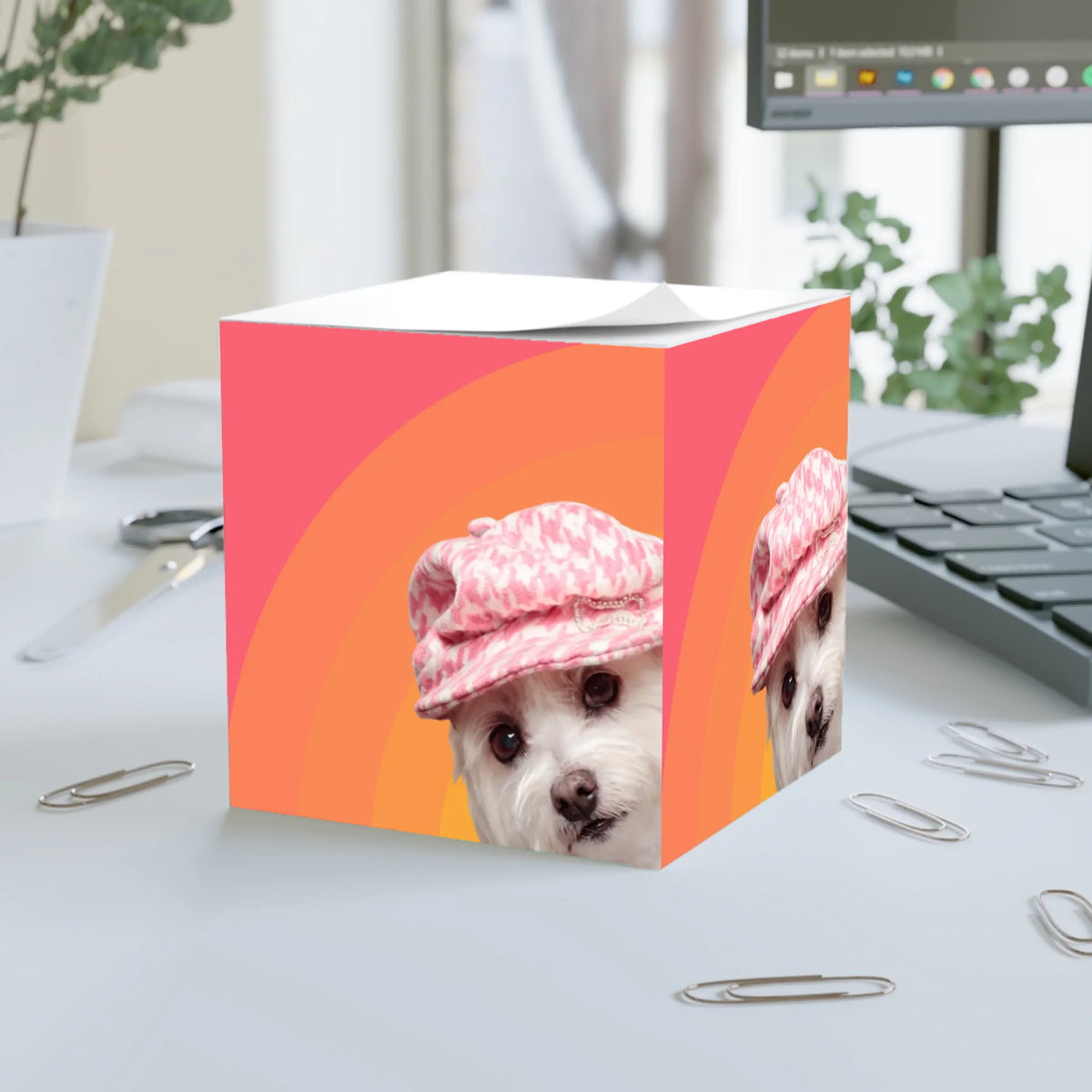 Big Glow Energy personalised note cube on a desk, showing a white dog in a pink houndstooth cap on the Sunrise colour, with orange and pink retro arches