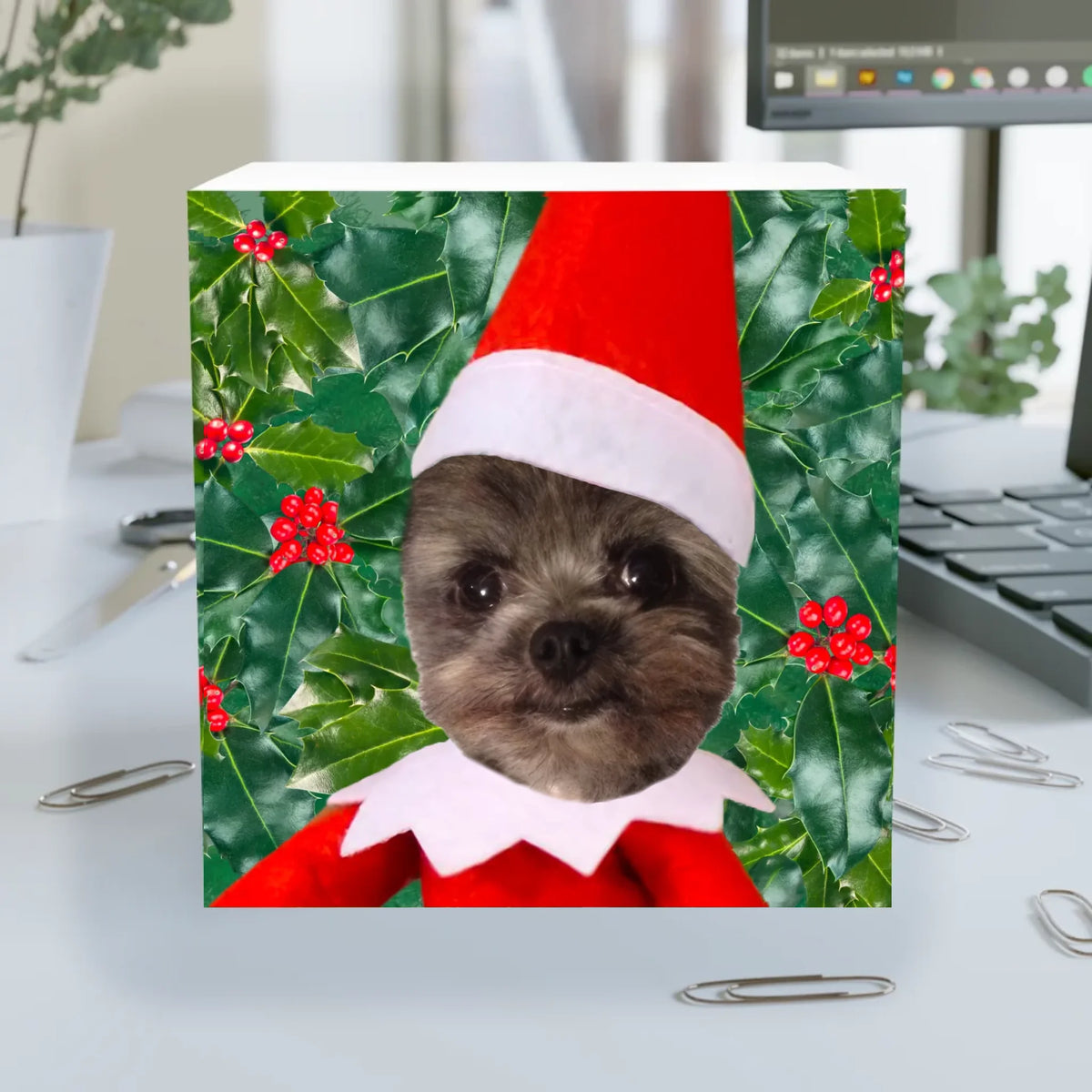 Close-up of the Official Elf Business design: a dog's face in an elf hat and collar framed by holly and red berries